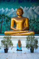 A girl at the foot of a buddha