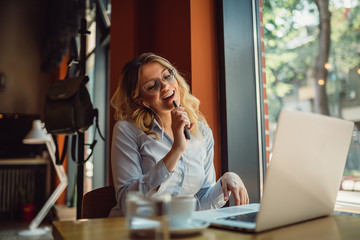 Beautiful blond woman enjoying favorite music and using mobile phone as microphone to sing