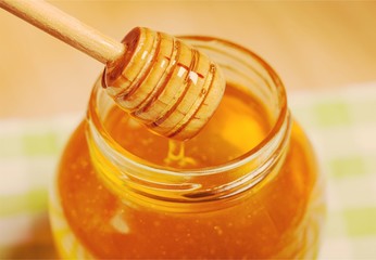 Fototapeta na wymiar Honey and wooden spoon on background