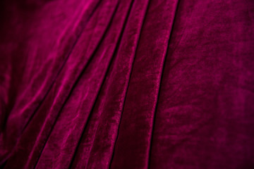 Red velvet fabric folded in an accordion, lies on the table view diagonally, folds on the fabric