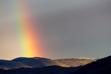 Beautiful and surreal view of part of a rainbow over some hills