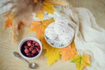 Obraz na płótnie Canvas Homemade marshmallow with mint and raspberry, surrounded by yellow autumn leaves, on a light background