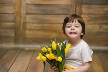A small child with a bouquet of yellow tulips. A boy with a gift
