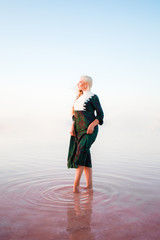 Young woman walking on Dead Sea with beautiful sky at pink sunrise