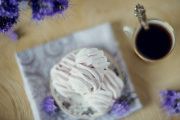 Homemade marshmallow on a saucer with appliances and a Cup of coffee, on a light background with purple flowers. The concept of a cozy autumn dessert.