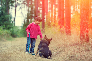 Happy little girl with dog walking in the forest