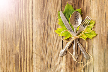 Autumn dinner place setting for Thanksgiving holiday with colorful maple leaves on rustic wooden boards