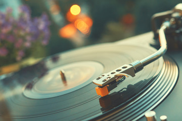 Turntable vinyl record player on the background of a sunset over the lights city. Sound technology...