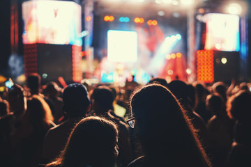 Blurred music festival of the youth of pop music. Laser show on stage. A crowd of fans with their hands up. A bright abstract background is perfect for any design. Blurred background bokeh background 