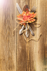 Autumn dinner place setting for Thanksgiving holiday with colorful maple leaves on rustic wooden boards