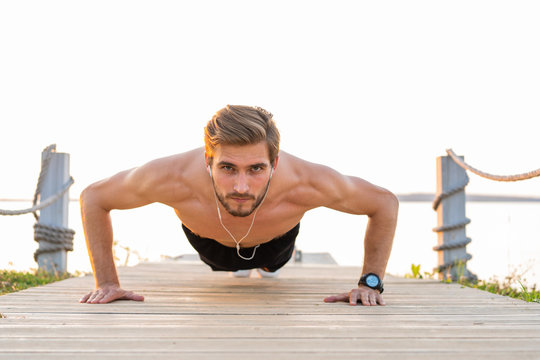Picture of a young athletic man doing push ups outdoors