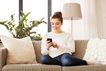 technology and people concept - smiling woman with smartphone at home