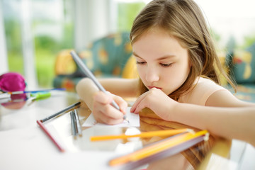 Cute little girl drawing with colorful pencils at a daycare. Creative kid painting at school.
