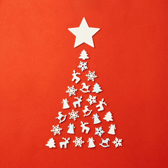 Fototapeta na wymiar Christmas card with place for your text. A large Christmas tree on a red background, laid out with wooden figures in the form of a snowflake, a Christmas tree, a horse, a deer, a bell.