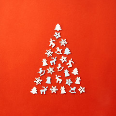 Christmas card with place for your text. A large Christmas tree on a red background, laid out with wooden figures in the form of a snowflake, a Christmas tree, a horse, a deer, a bell