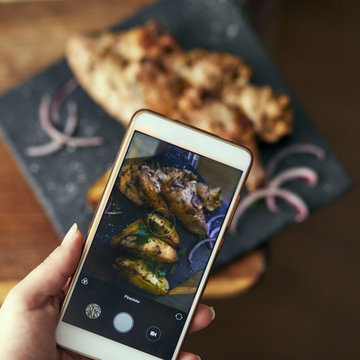 Chicken dish is shot on the phone, on a wooden board, under natural light