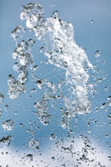 Splashing water with drops on the sky background