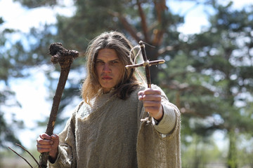 A man in a cassock spends a ritual in a dark forest
