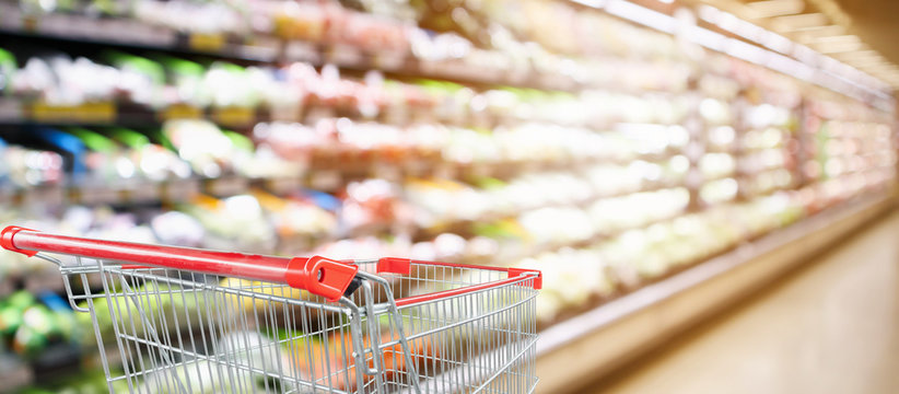 Supermarket Grocery Store With Fruit And Vegetable Shelves Interior Defocused Background With Empty Red Shopping Cart