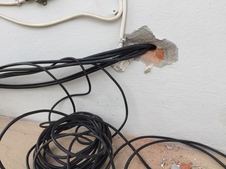 break in the wall with protruding electrical wires, Electric wire sticking out of a white wall, crack hole wall with electric wires