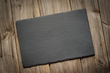 Slate blackboard on old wooden background. Flat lay.Top view.