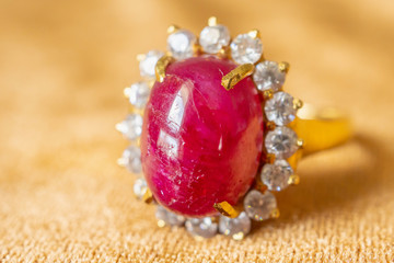 Jewelry red ruby ring on golden fabric background close up