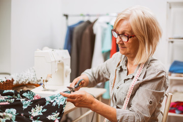 Adult woman is sewing in her studio. 