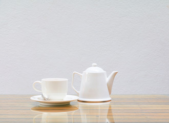 coffee cup and teapot white On the glass table wooden and a cement wall background. copy space