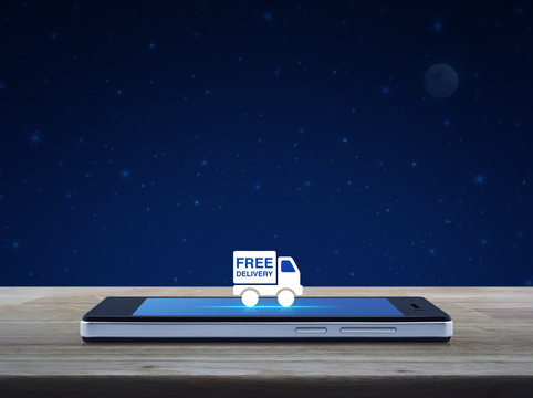 Free delivery truck flat icon on modern smart mobile phone screen on wooden table over fantasy night sky and moon, Business transportation online concept