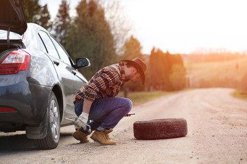 Man is sitting on the road by the car