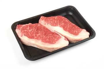 Raw beef steak in a tray isolated on white background.