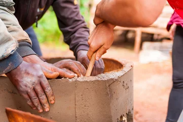 Fototapete Afrika Nahaufnahme von schwarzen und weißen Händen, die zusammenarbeiten, um Zementwasserbrunnen im afrikanischen Dorf zu bauen?