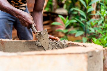young black african man hands working with cement to build water well in africa village