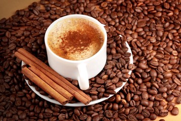 Cappuccino or latte surrounded by coffee beans and cinnamon