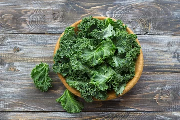 Poster Fresh green curly kale leaves on a wooden table. selective focus. rustic style. healthy vegetarian food © olepeshkina