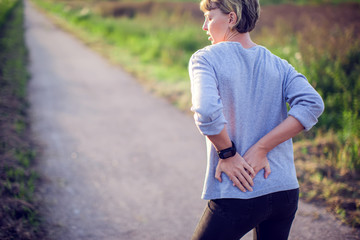 People, healthcare and problem concept - unhappy woman suffering from pain in back or reins outdoor