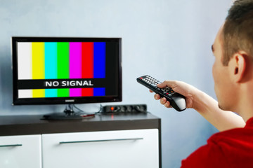 Remote control in hand in front of TV. Couch potato. No signal screen banner