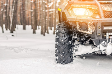 Close-up ATV 4wd quad bike in forest at winter. 4wd all-terreain vehicle stand in heavy snow with...