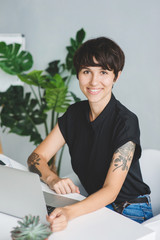 Attractive young businesswoman working on laptop and smiling while sitting at her desk