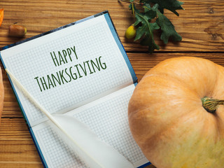 Happy thanksgiving day with pumpkin, acorns and congratulatory inscription on wooden background