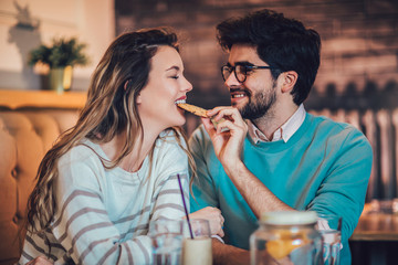  Beautiful loving couple sitting in a cafe sharing cookie. Love and romance concept.