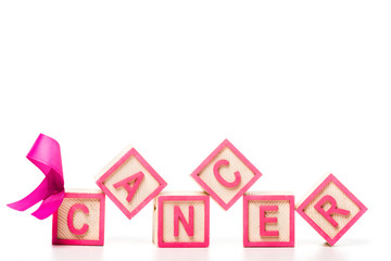 close-up view of pink ribbon and wooden cubes with word cancer isolated on white