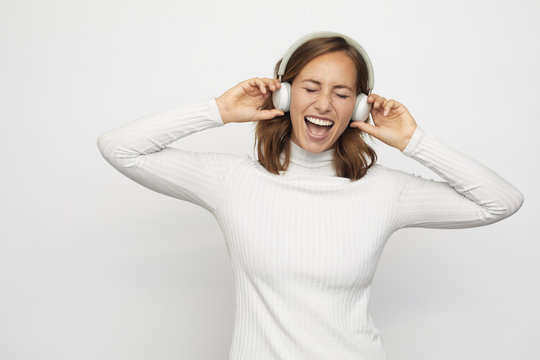 young woman with headphones sings eyes closed
