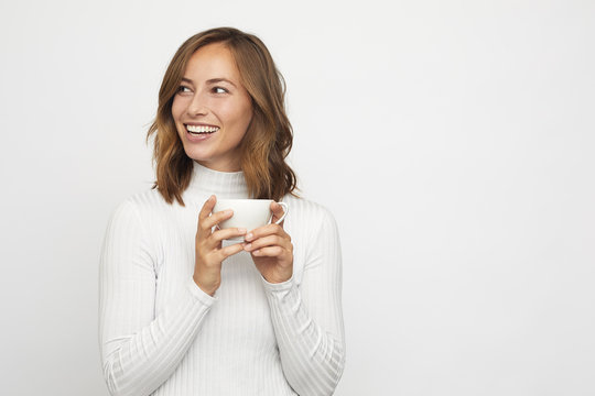 young woman with cup of coffee looks left