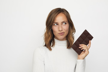 portrait of young healthy woman holding some chocolate thinking looks right