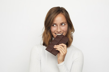 portrait of young woman biting in a pieace of chocolate looks Left