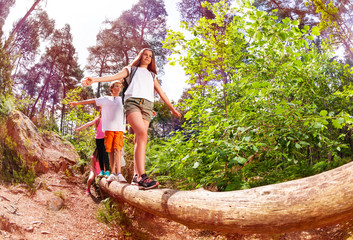 Naklejka na ściany i meble Boys and girls walk on the big log in forest