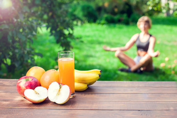 Lifestyle, sport and healthcare. A woman during yoga exercises outdoor. Healthy food on the table