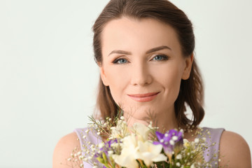 Fototapeta premium Beautiful woman with bouquet of flowers on light background