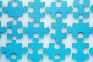 Elements of a puzzle of blue color on a white table.